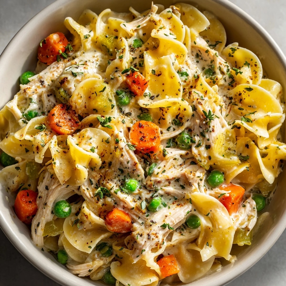 One-Pot Chicken Pot Pie Noodles with peas: a steaming bowl filled with creamy pasta and tender chicken.