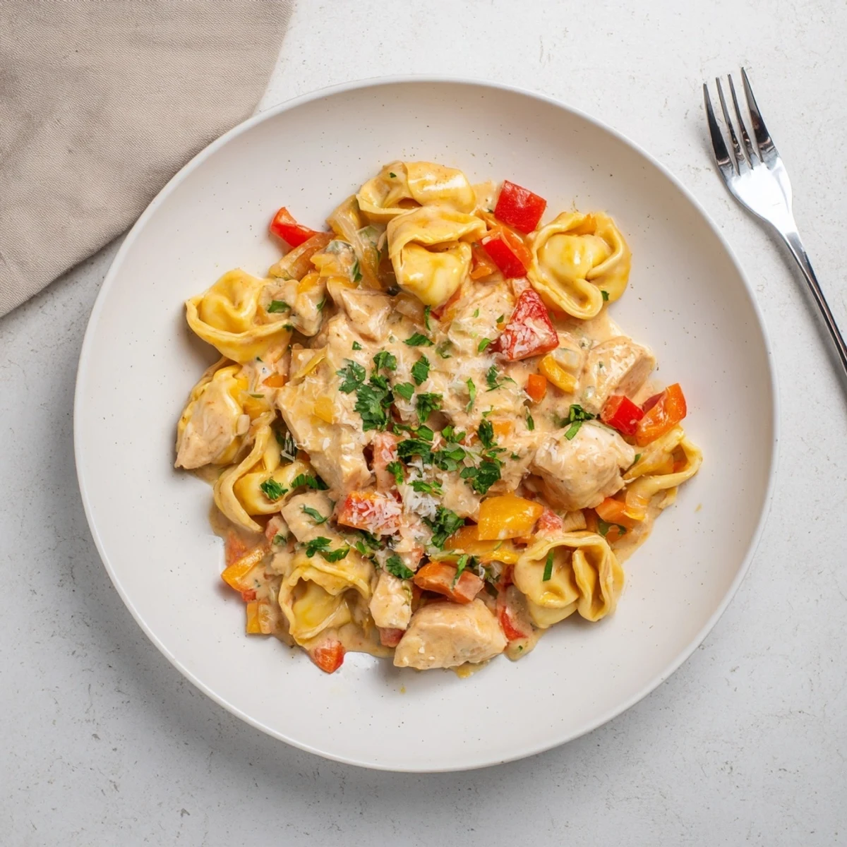Zesty Cajun Garlic Parmesan Chicken Tortellini served with fresh parsley and creamy sauce.  