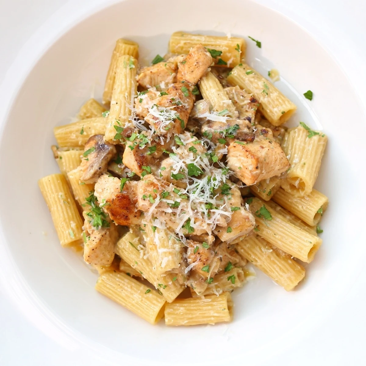 Steaming creamy garlic Parmesan chicken rigatoni, garnished with fresh parsley and extra cheese.