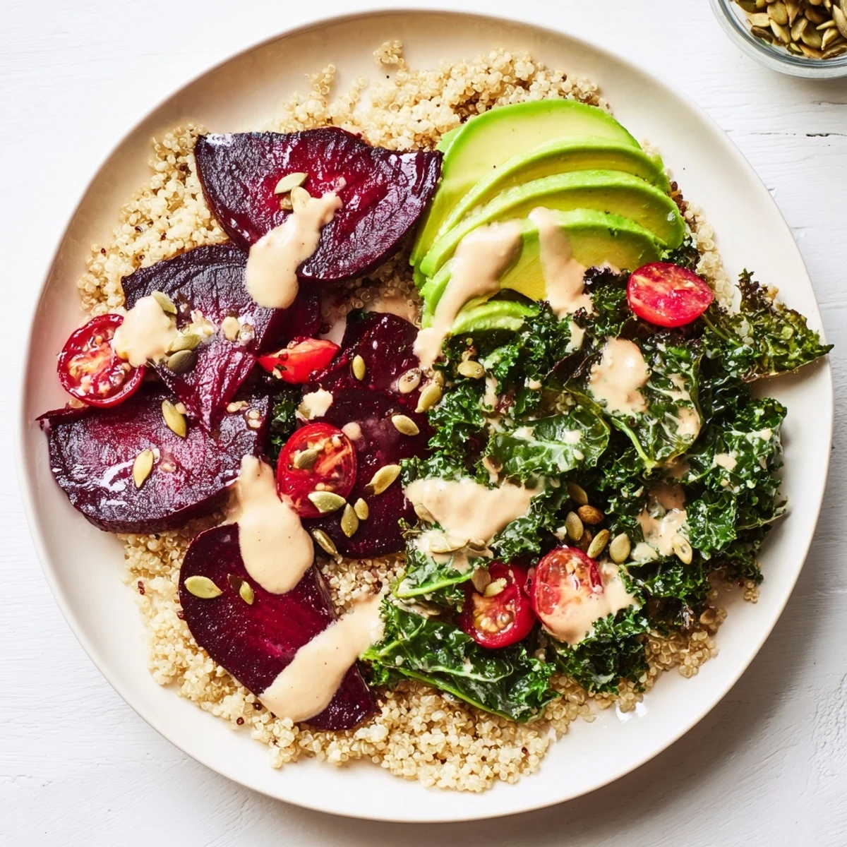Bright and appetizing, this Quinoa, Kale & Roasted Beet Bowl is topped with creamy tahini dressing and pepitas.