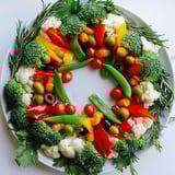 Vibrant Garland Veggie Wreath featuring bright bell peppers, tomatoes, and broccoli, sure to impress.