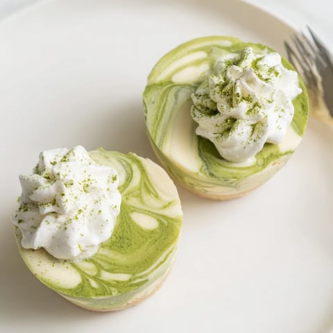 Matcha Swirl Snowdrift Cheesecake Cups, a layered no-bake dessert with a refreshing matcha flavor.