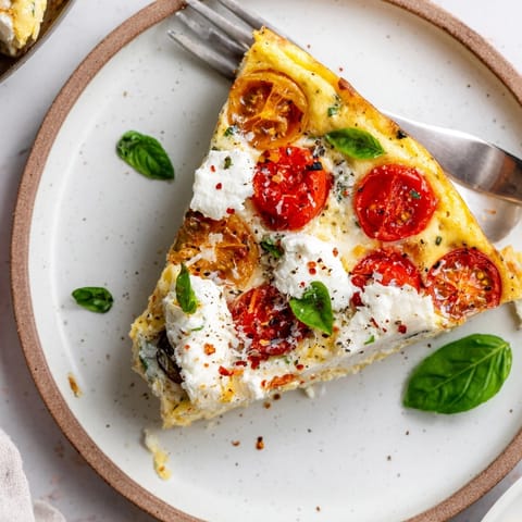 Close up of a sliced Ricotta Tomato Basil Frittata, showing creamy layers and fresh herbs.
