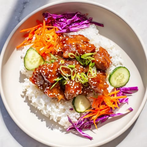 A steaming bowl of Sriracha Honey Chicken, the sweet and spicy sauce coating tender chicken pieces.