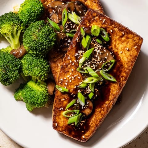 Crispy, pan-fried Sautéed Tofu Steak beside vibrant broccoli and shiitake mushrooms.