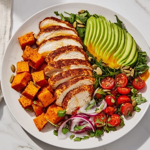 A colorful Avocado and Sweet Potato Chicken Bowl featuring avocado slices and fresh cilantro, is ready to be eaten.