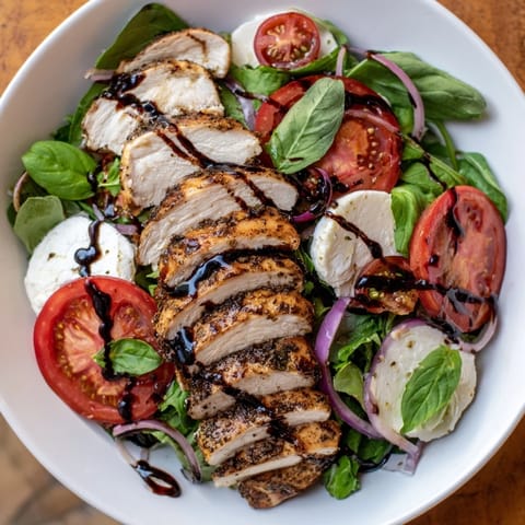 A close-up of a flavorful Caprese Chicken Salad, drizzled with tangy balsamic reduction.