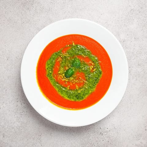 Velvety tomato soup with pesto swirl, paired with crusty bread, perfect for a cozy, comforting vegetarian meal.