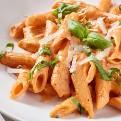 A skillet of creamy roasted red pepper pasta topped with extra Parmesan cheese.  