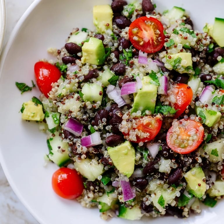 Freshly tossed quinoa black bean salad showcasing juicy tomatoes, perfect for a healthy vegetarian lunch.
