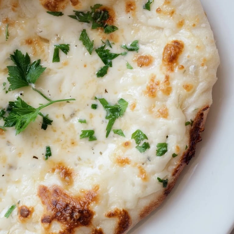 A close-up of Creamy Garlic White Pizza showing the luscious garlic cream sauce and melted cheese topping.