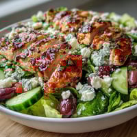 Greek Salad Bowl with Grilled Chicken, fresh and colorful, featuring juicy grilled chicken over crisp lettuce, tomatoes, cucumbers, and feta.
